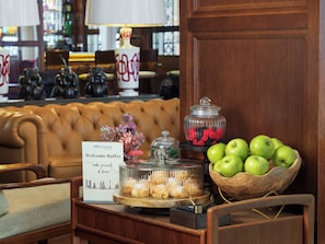 Une table de buffet avec un panneau indicateur, un saladier de pommes vertes, un bocal rempli de baies et un vase décoratif.