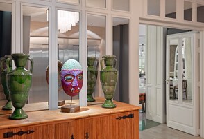 Una habitación con un aparador de madera que muestra jarrones verdes y una escultura abstracta colorida.