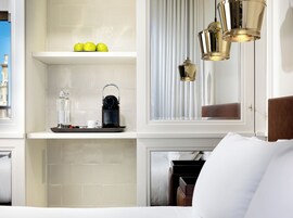 Habitación de hotel con kitchenette, una cama, un ventanal con cortinas y una lámpara colgante.