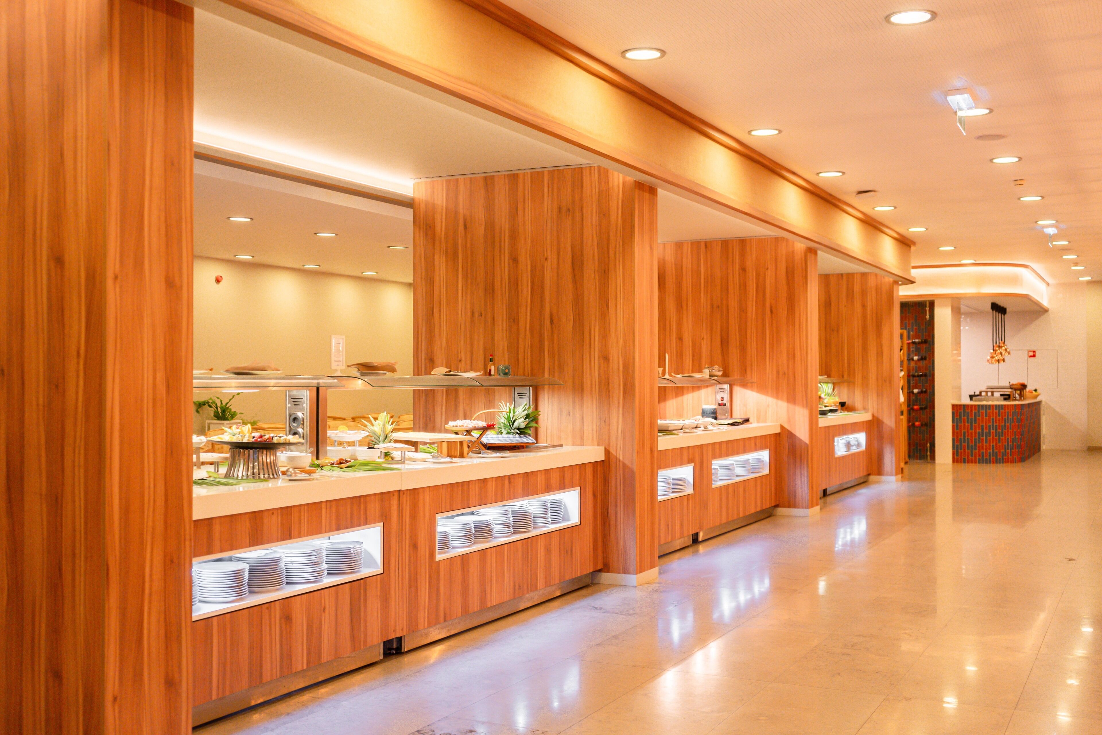 Een moderne hotellobby met houten receptiebalies, een gepolijste vloer en inbouwverlichting.