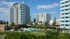 A hotel with multiple high-rise buildings, a swimming pool, and lush greenery. - The Anchor Troia River (Grandola)