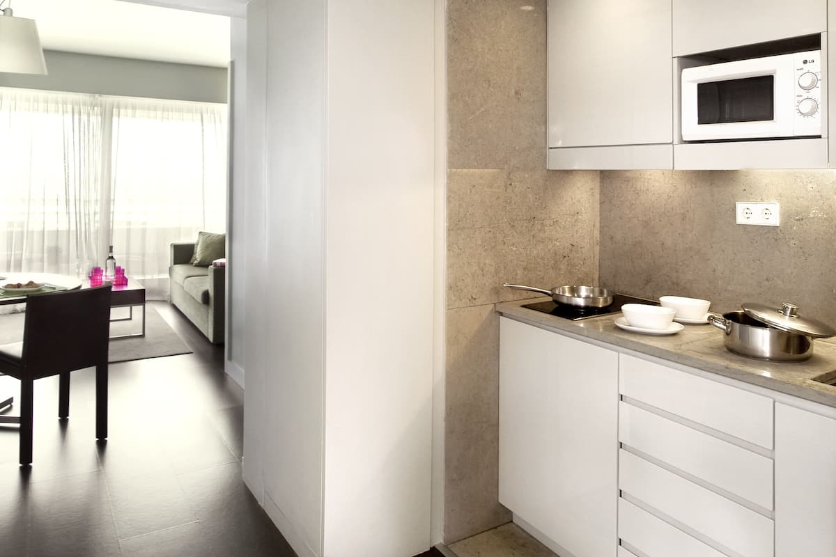 Una cocina moderna con armarios blancos, un microondas y un comedor con mesa y sillas.