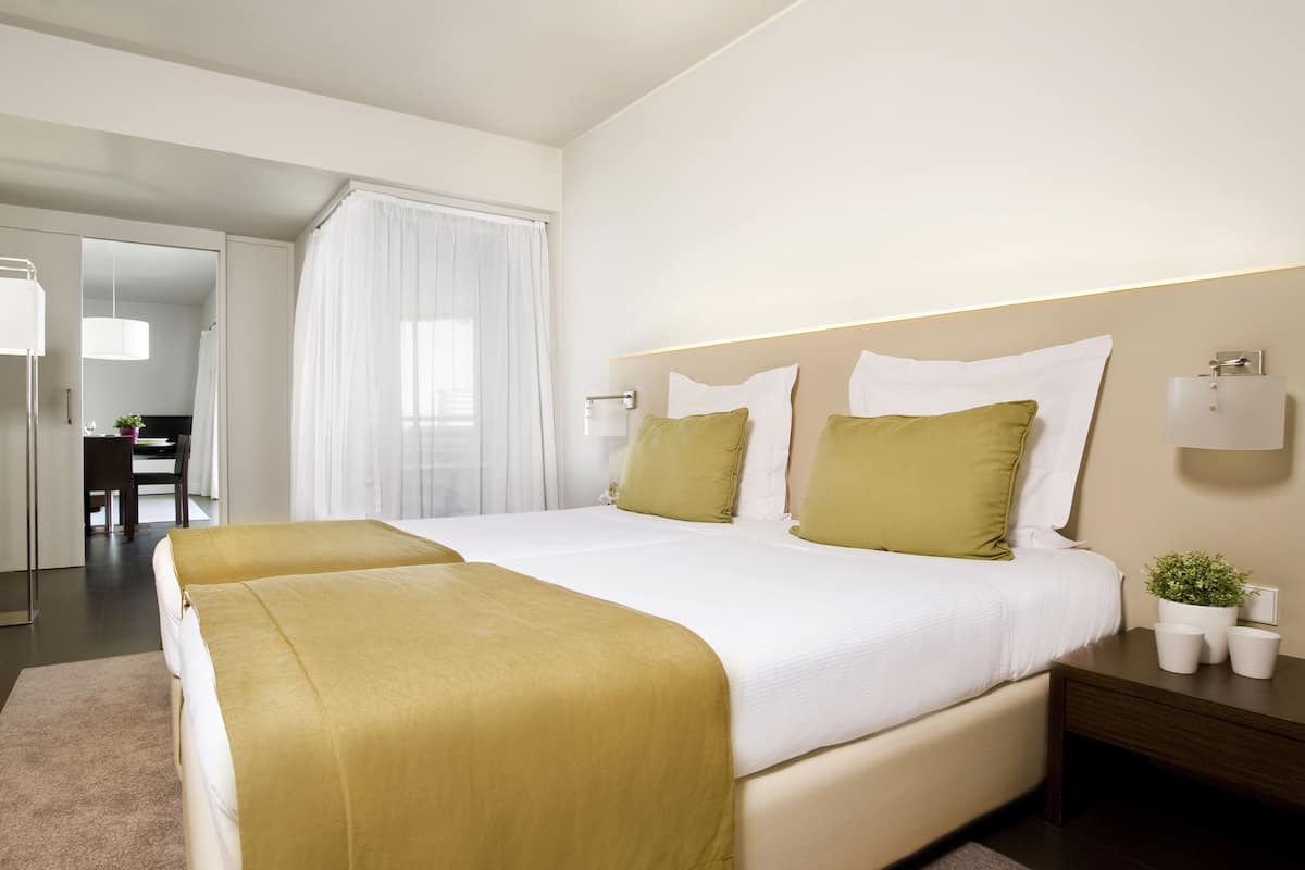 Habitación de hotel con dos camas, un escritorio y una silla.