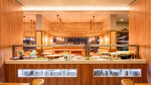 A buffet setup with a wooden counter, multiple serving stations, and a variety of food items. - The Anchor Troia River (Grandola)