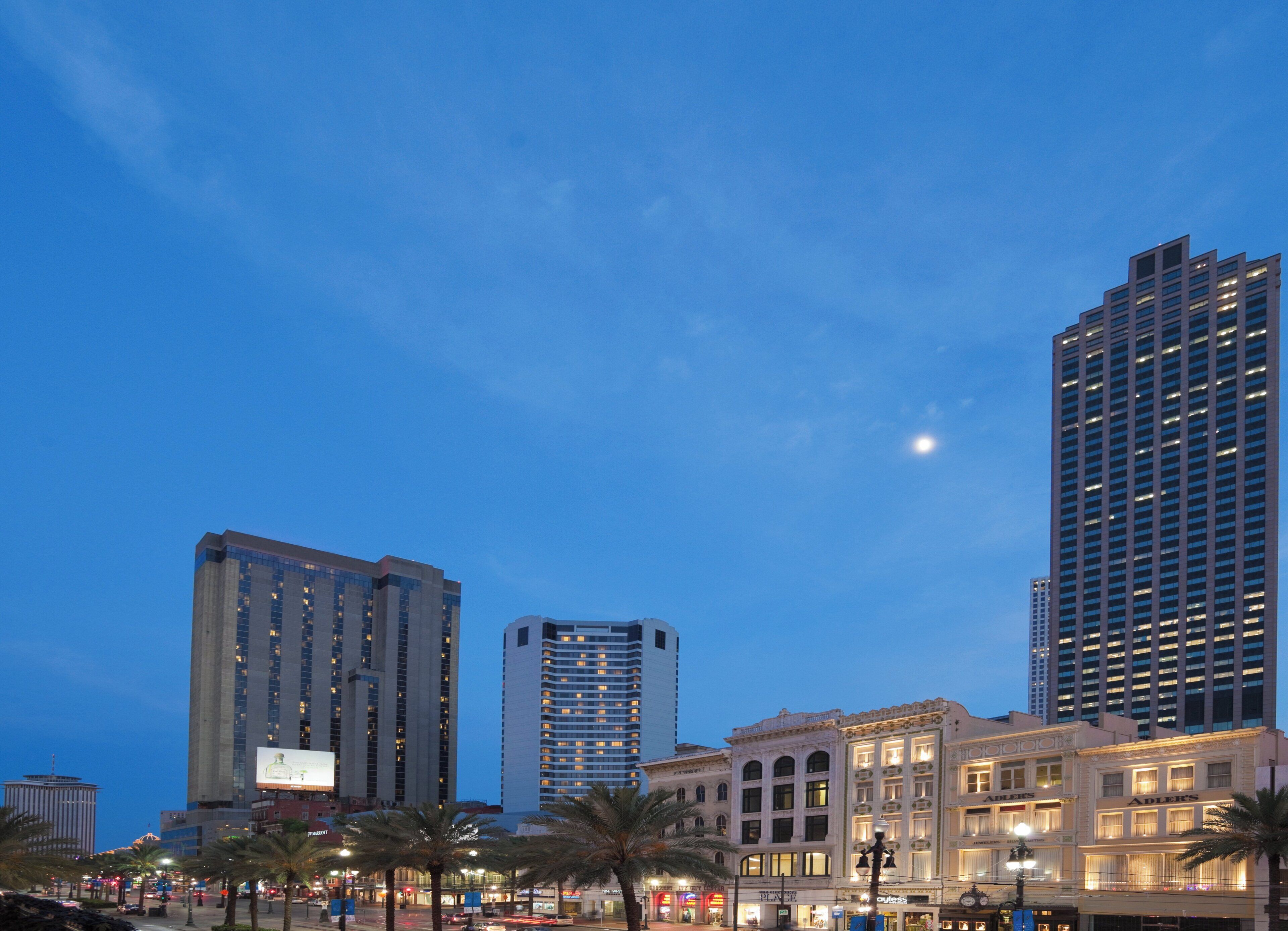 A cityscape with modern high-rise buildings and a historic building with illuminated signage.