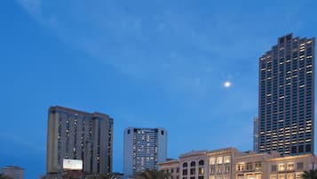 A cityscape with modern high-rise buildings and a historic building with illuminated signage.