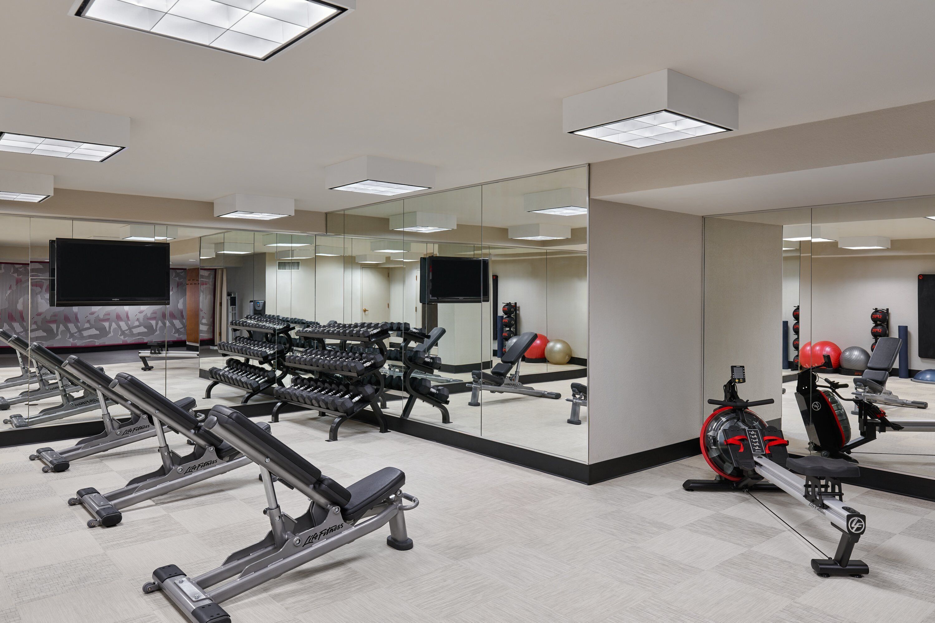 Une salle de sport équipée de divers appareils d’exercice, notamment des tapis de course, des appareils de musculation et un rameur.