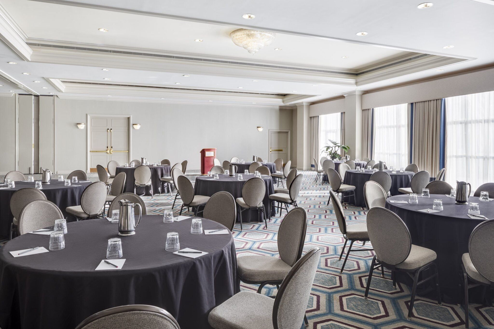 A conference room with multiple round tables, chairs, and a patterned carpet.