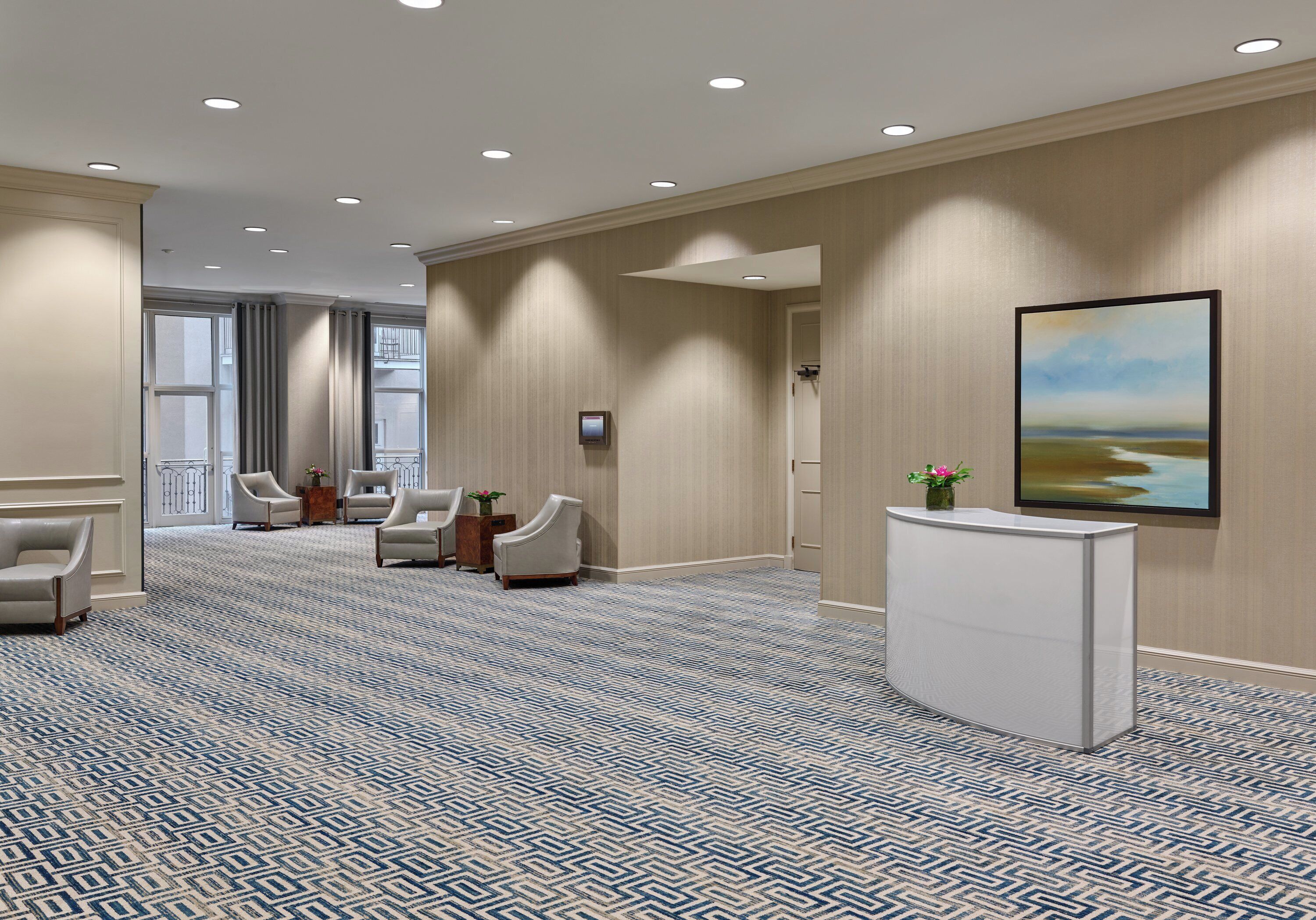 A hotel lobby with a reception desk, seating area, and a large window.