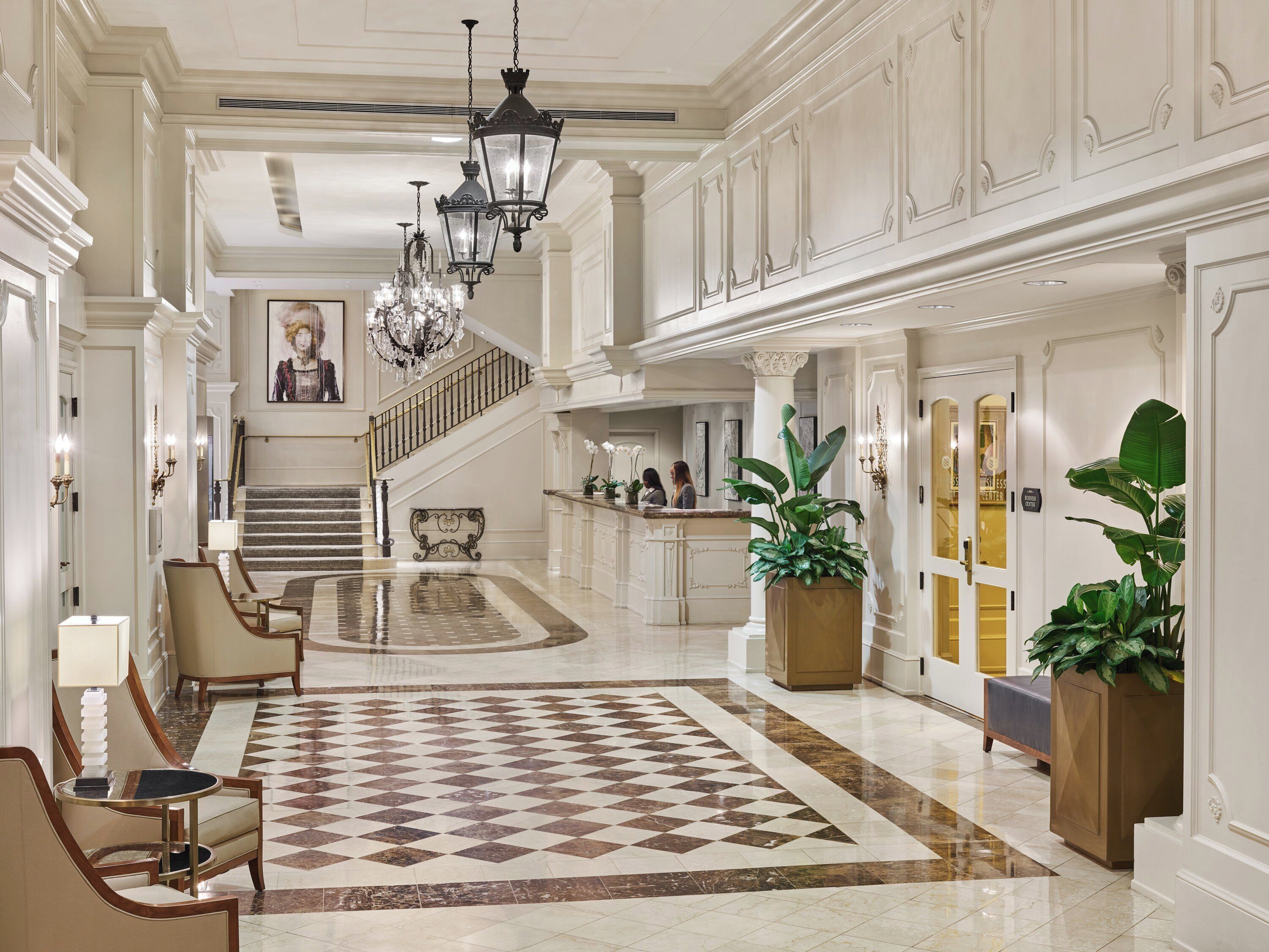 A spacious lobby with a checkered floor, a reception desk, and a staircase leading to upper floors.