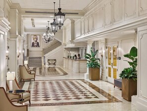 A spacious lobby with a checkered floor, a reception desk, and a staircase leading to upper floors. - Crowne Plaza New Orleans French Qtr - Astor by IHG (New Orleans)