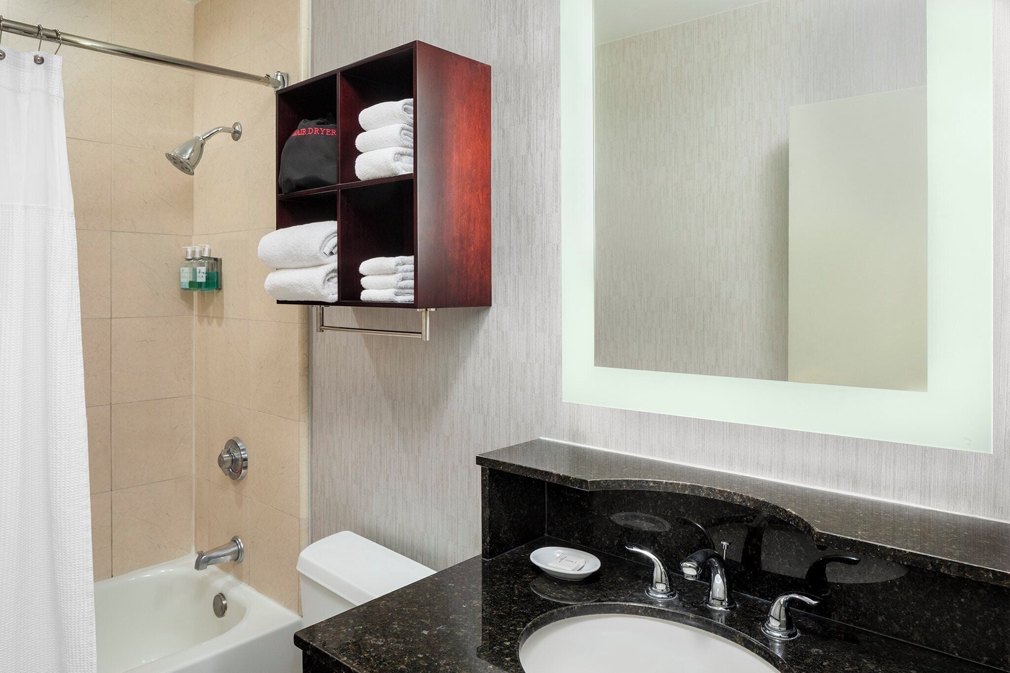 A bathroom with a shower, a toilet, a sink, and a mirror.