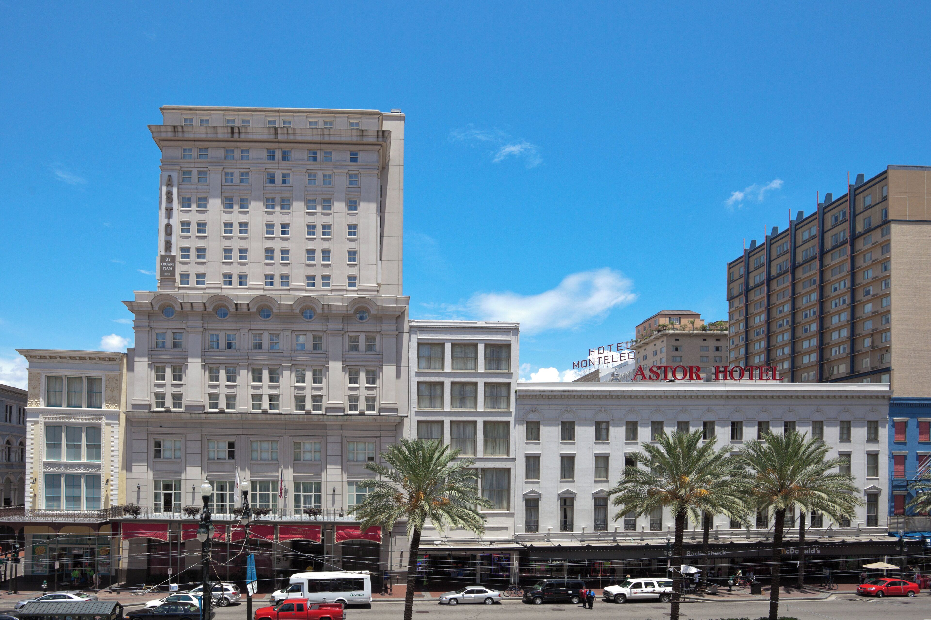 A hotel with a prominent 'ASTOR HOTEL' sign, a classic architectural style, and a street view with palm trees and parked vehicles.