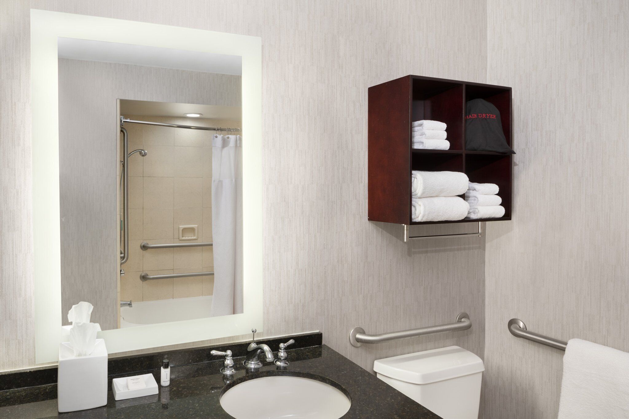 A modern bathroom with a large mirror, a sink, a toilet, and a towel rack.