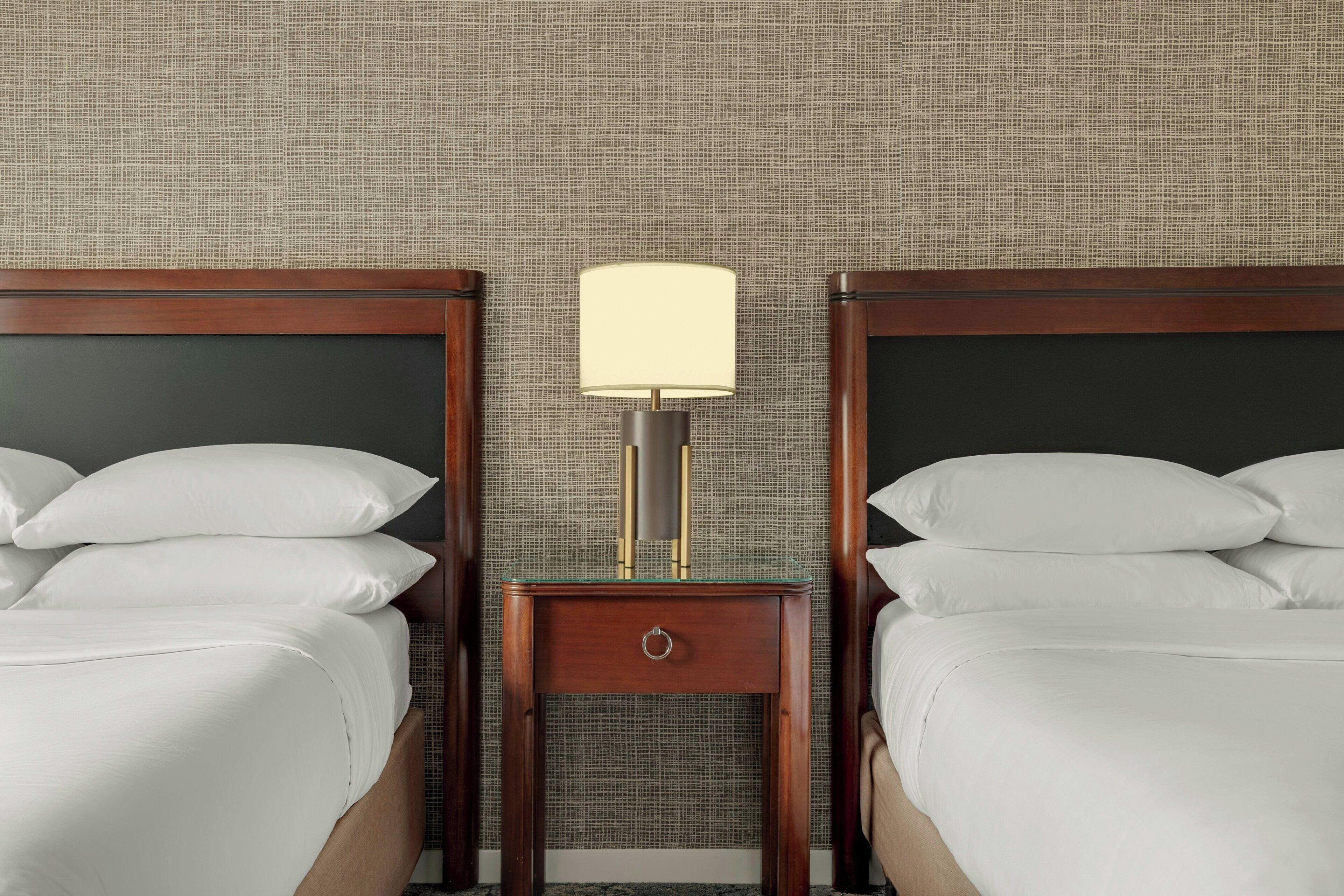 Une chambre d’hôtel avec deux lits, une table de chevet avec une lampe et un mur à motifs.
