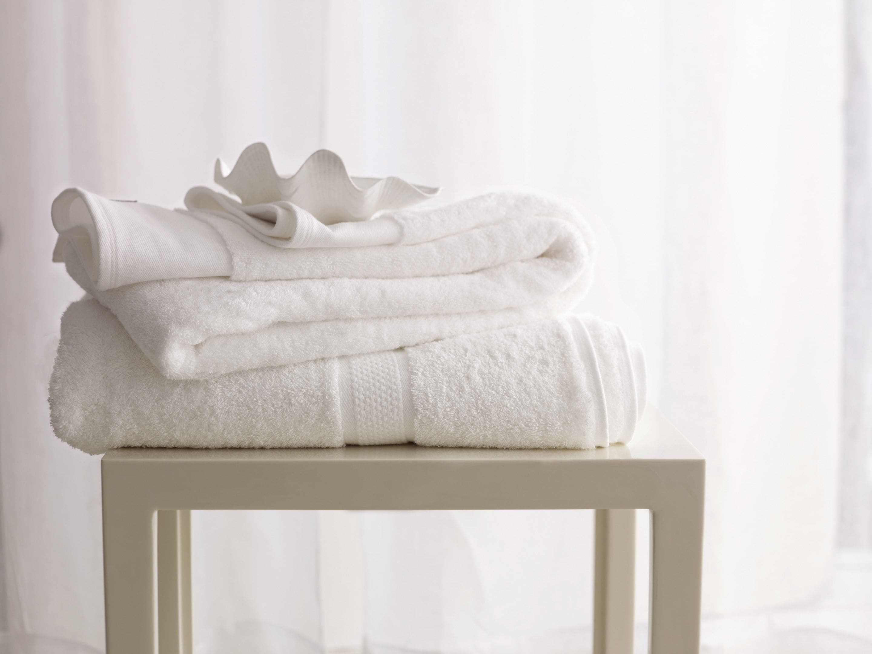 A stack of white towels on a white table against a white background.