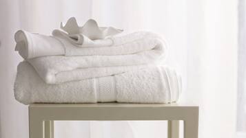 A stack of white towels on a white table against a white background.