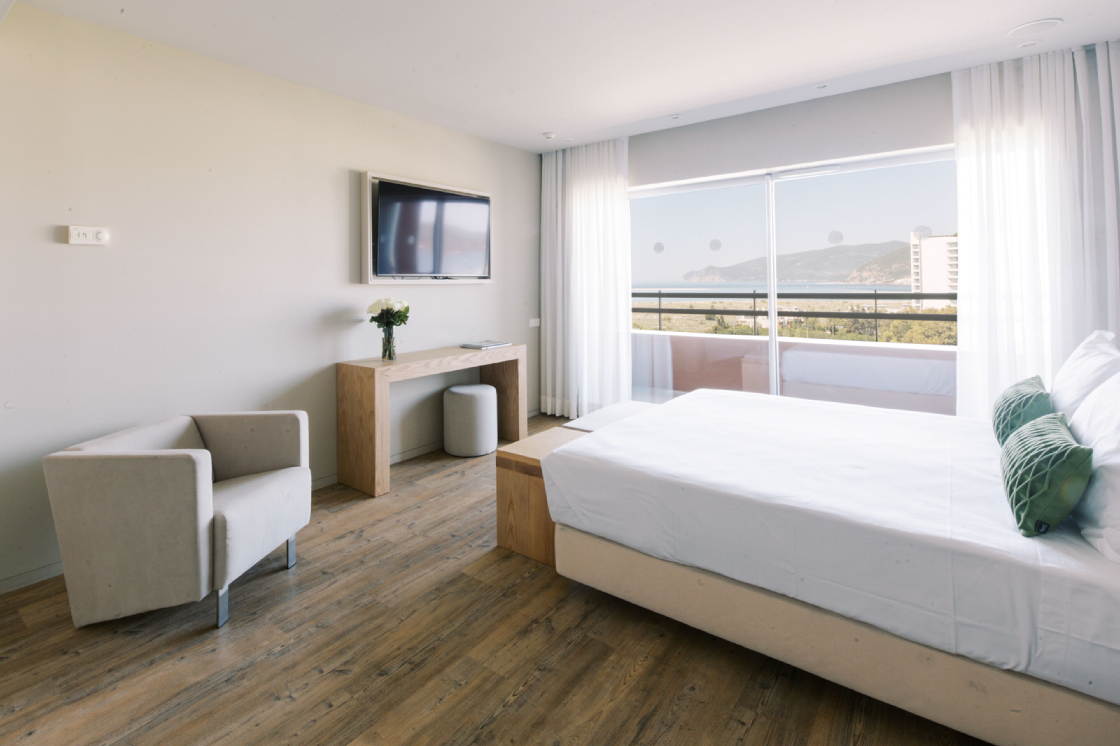 Una habitación de hotel moderna con una cama grande, un escritorio, una silla y un televisor en la pared.