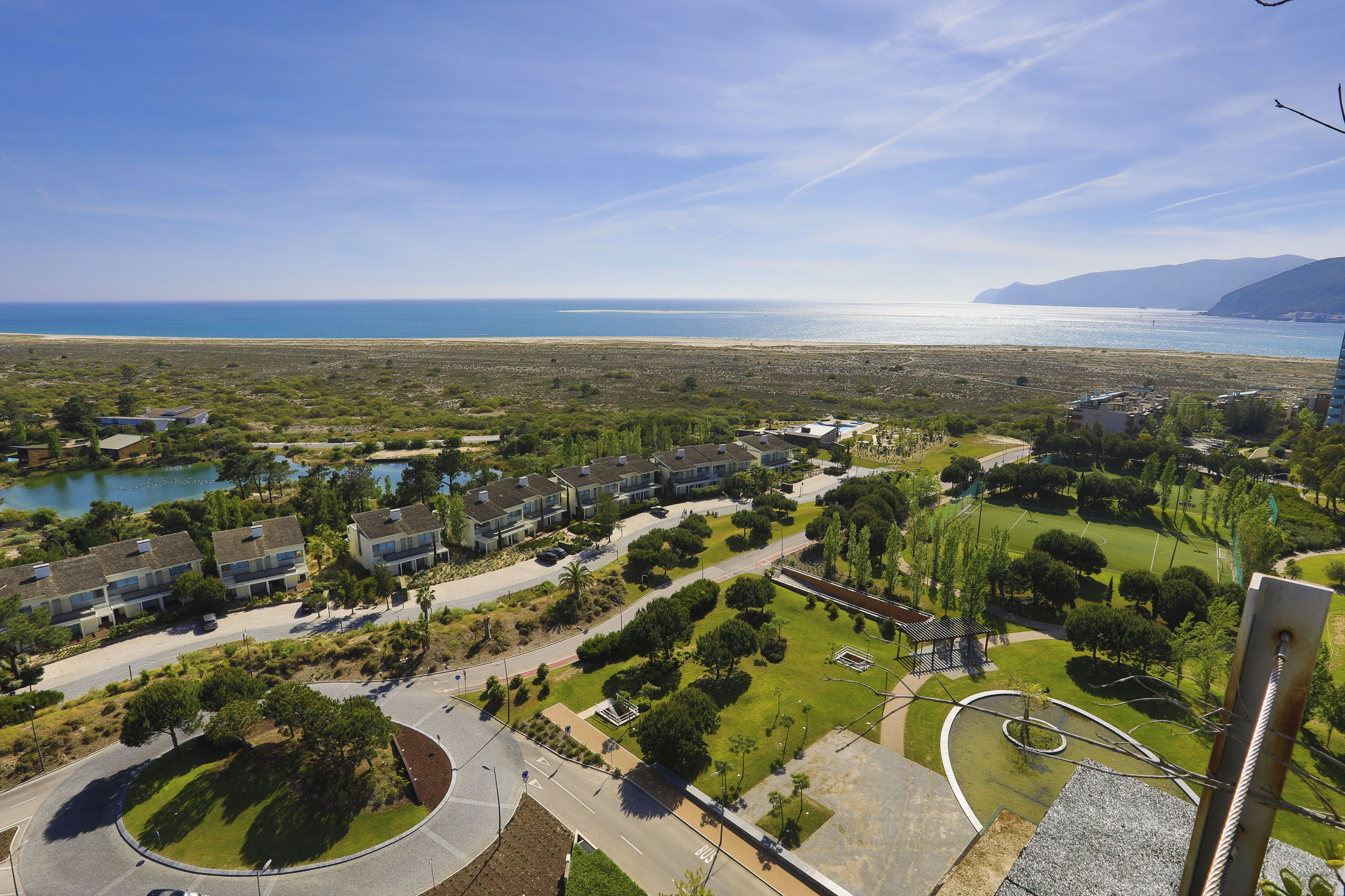 Zona residencial con vista al mar, una glorieta y un parque con árboles y un estanque.