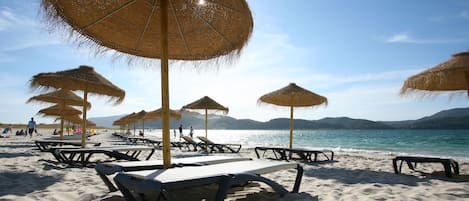 Sulla spiaggia, sabbia bianca, ombrelloni, pallavolo