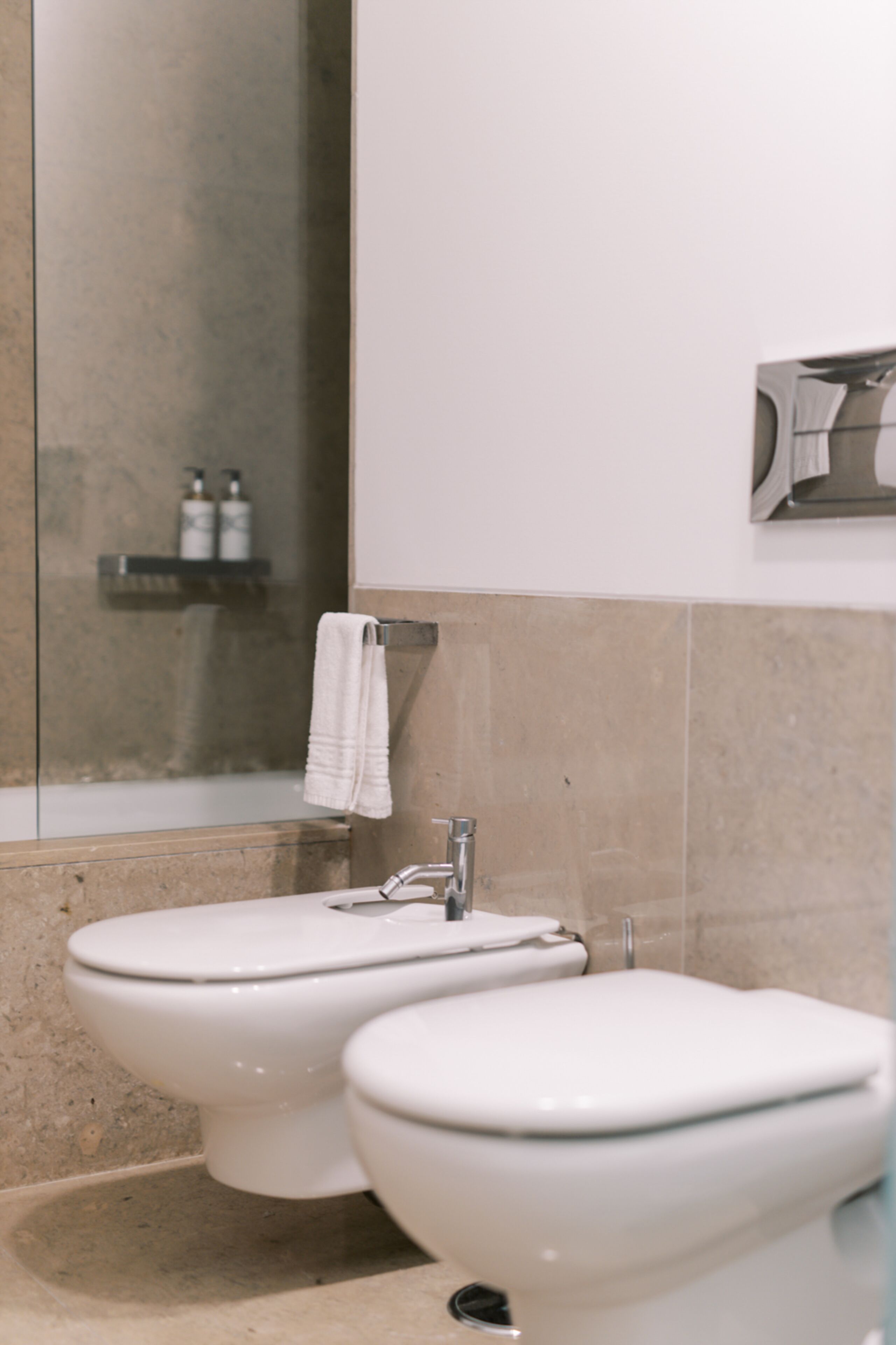 A bathroom with two toilets, a sink, and a shower.
