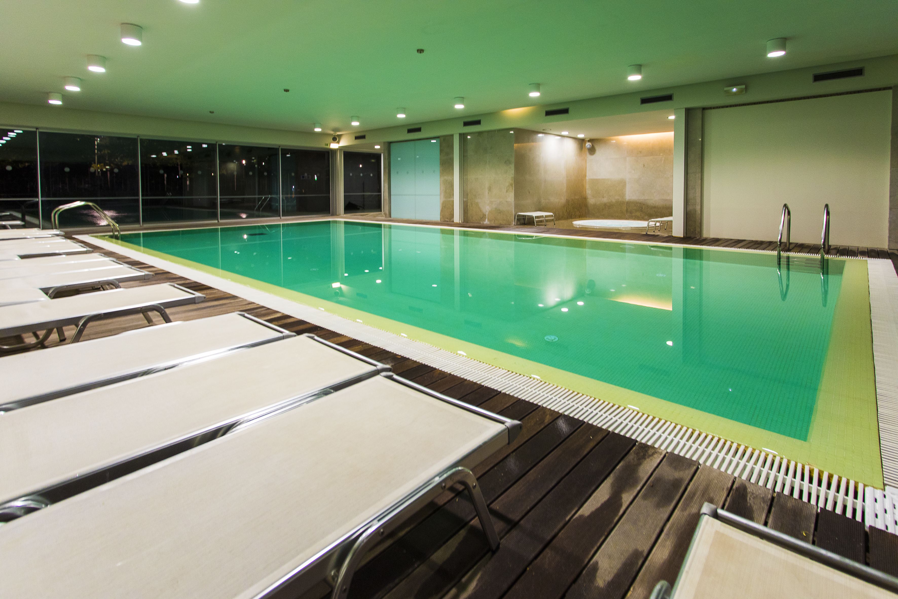 A swimming pool with lounge chairs and a wooden deck.
