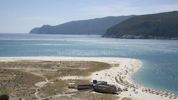 En la playa, arena blanca, sombrillas, vóleibol de playa