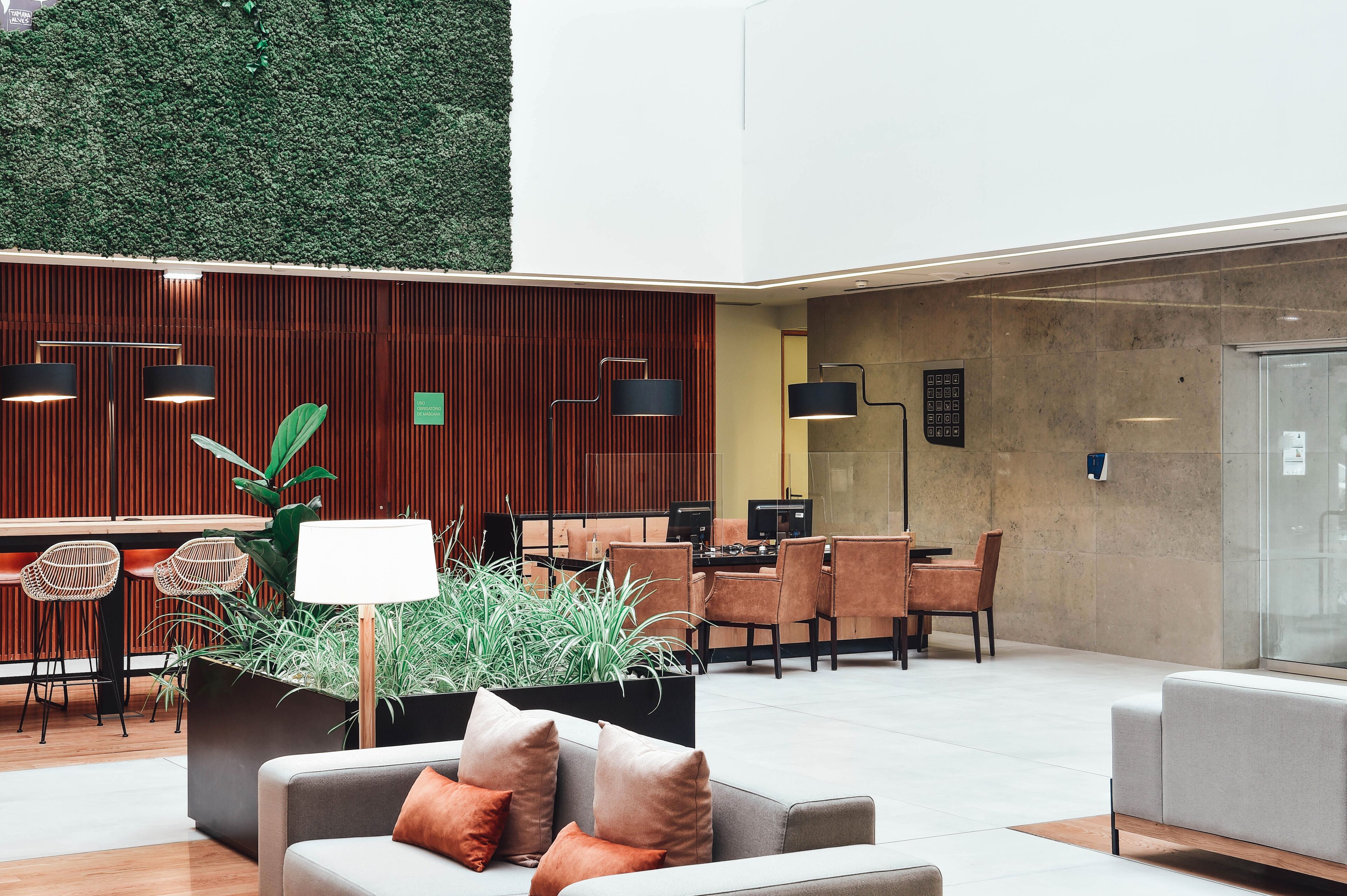 A modern lobby with a reception desk, seating area, and a green wall.