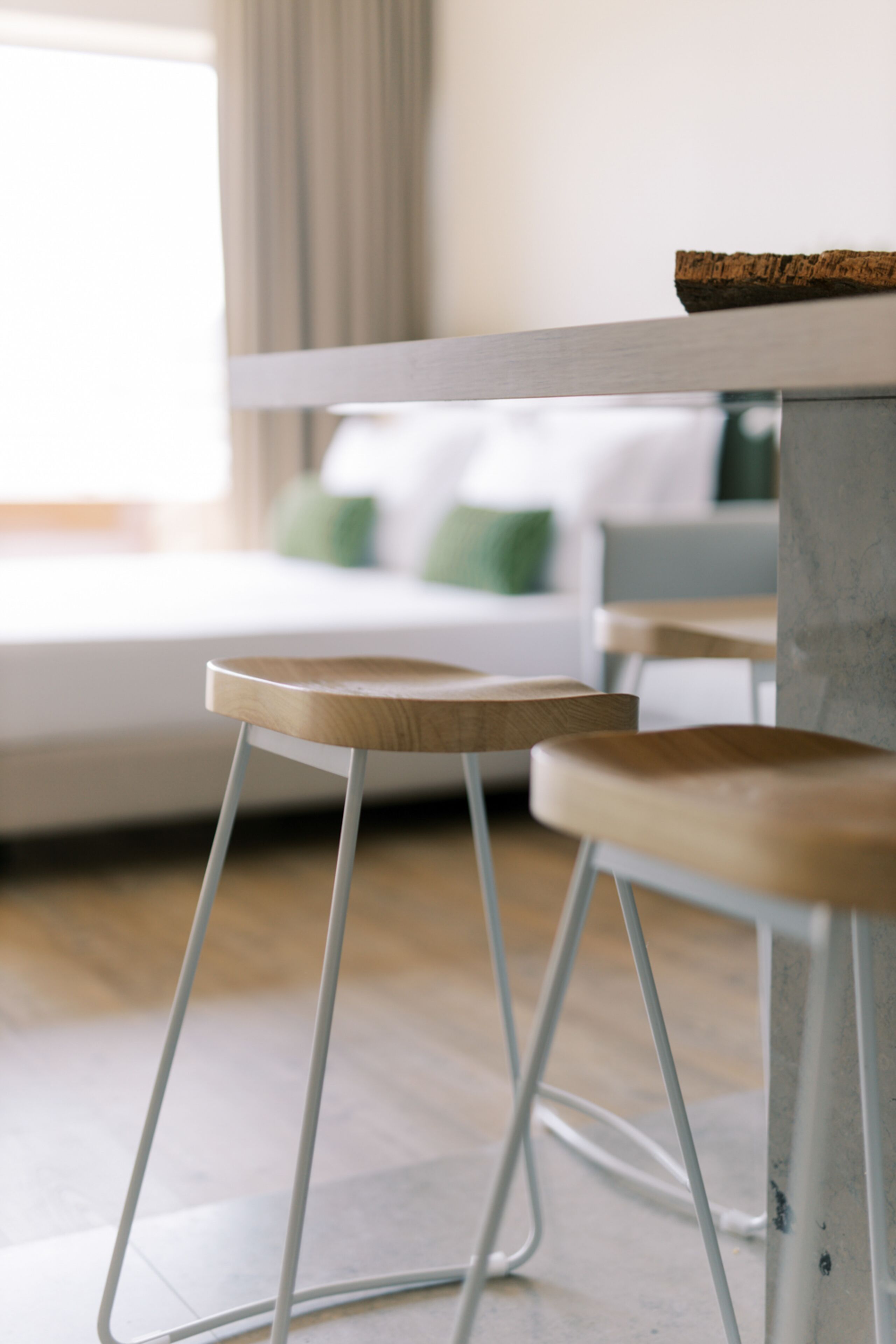 A modern room with a bed, a small table, and a stool.