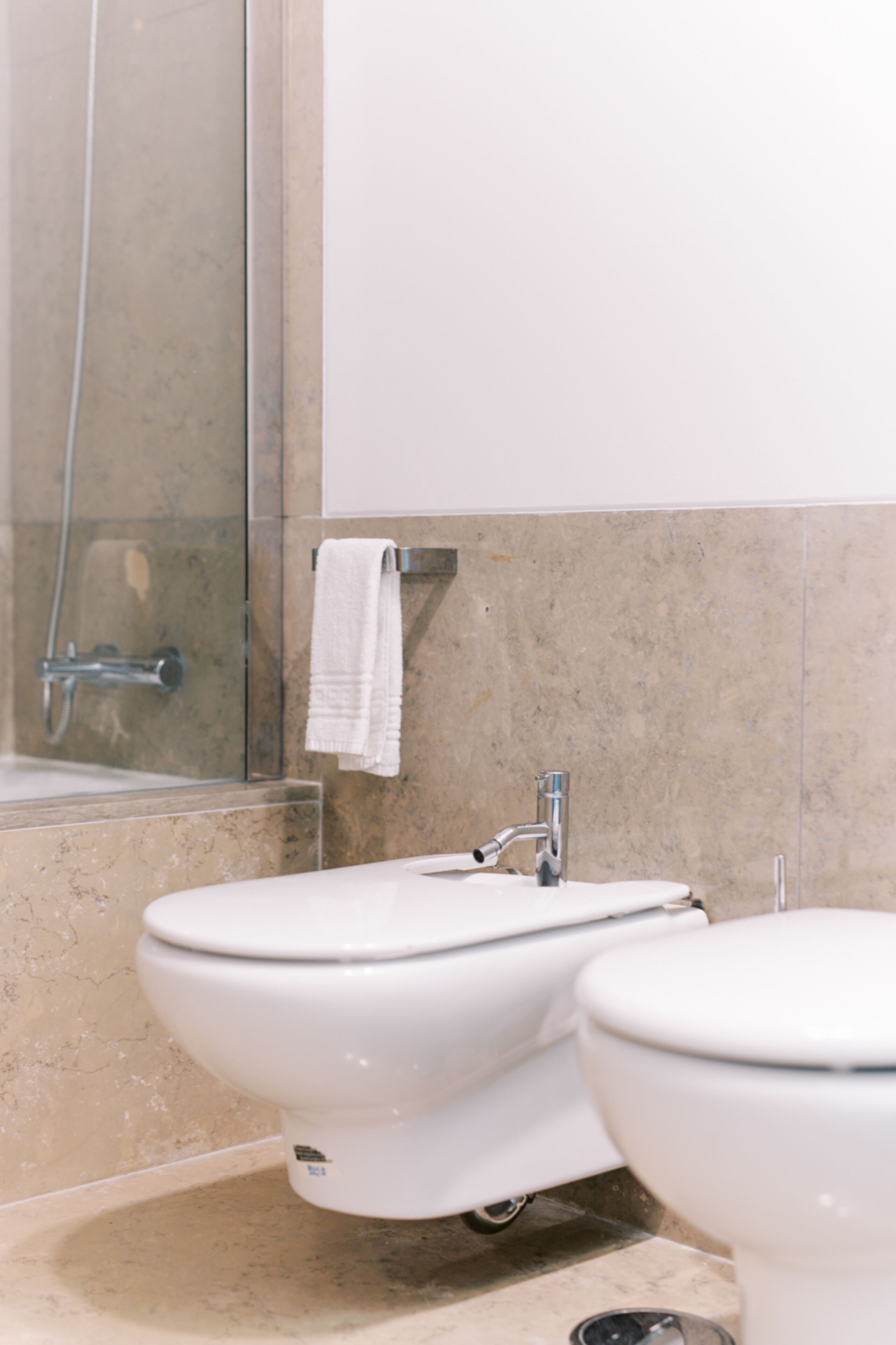 Un baño con ducha, dos inodoros y un perchero para toallas.