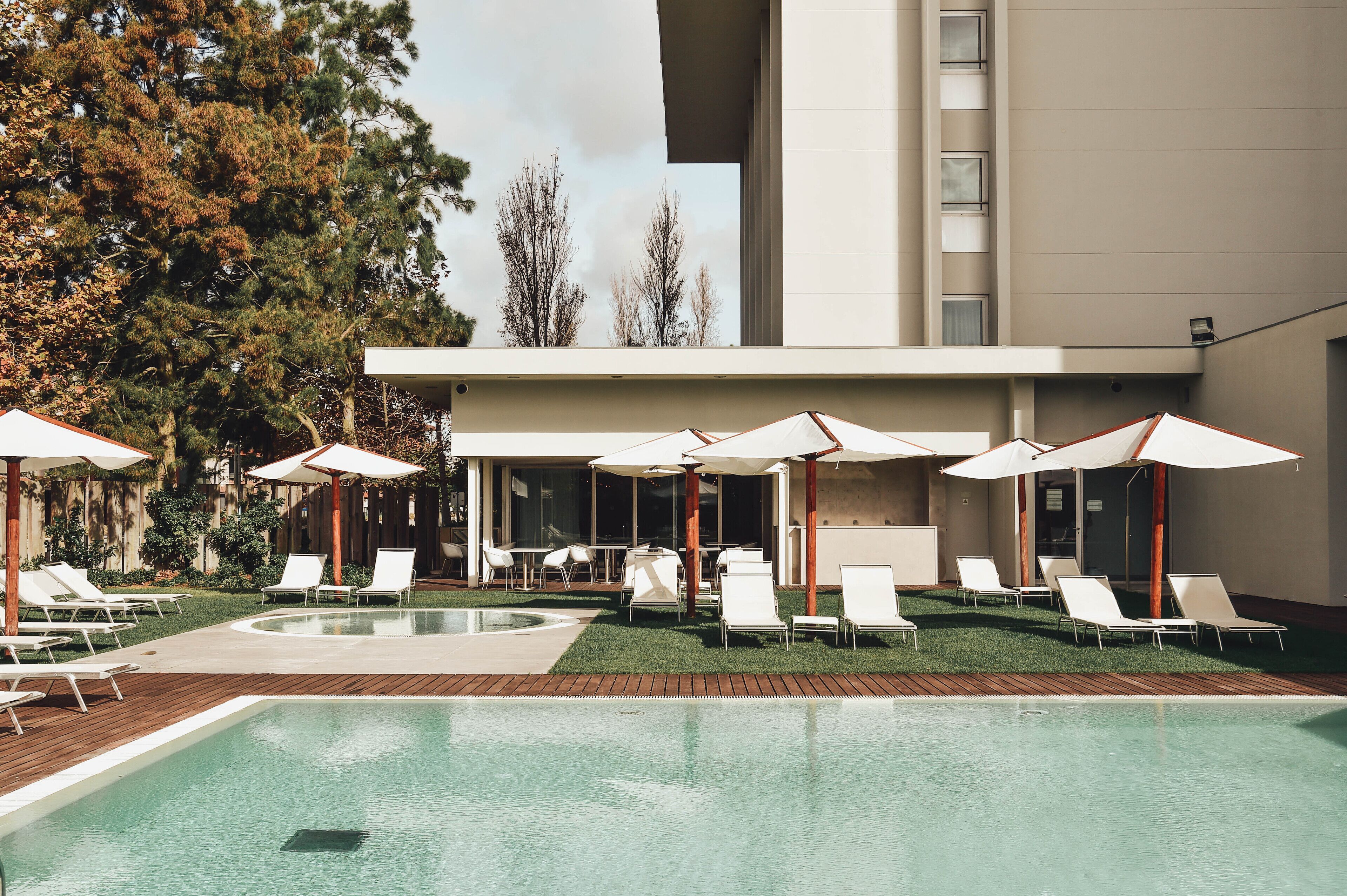 Um hotel moderno com piscina, espreguiçadeiras e guarda-sóis.