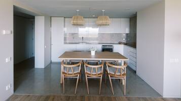 A modern kitchen with white cabinets, a wooden dining table, and four chairs.