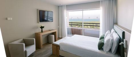 Una habitación de hotel moderna con una cama grande, un escritorio, una silla y un televisor.