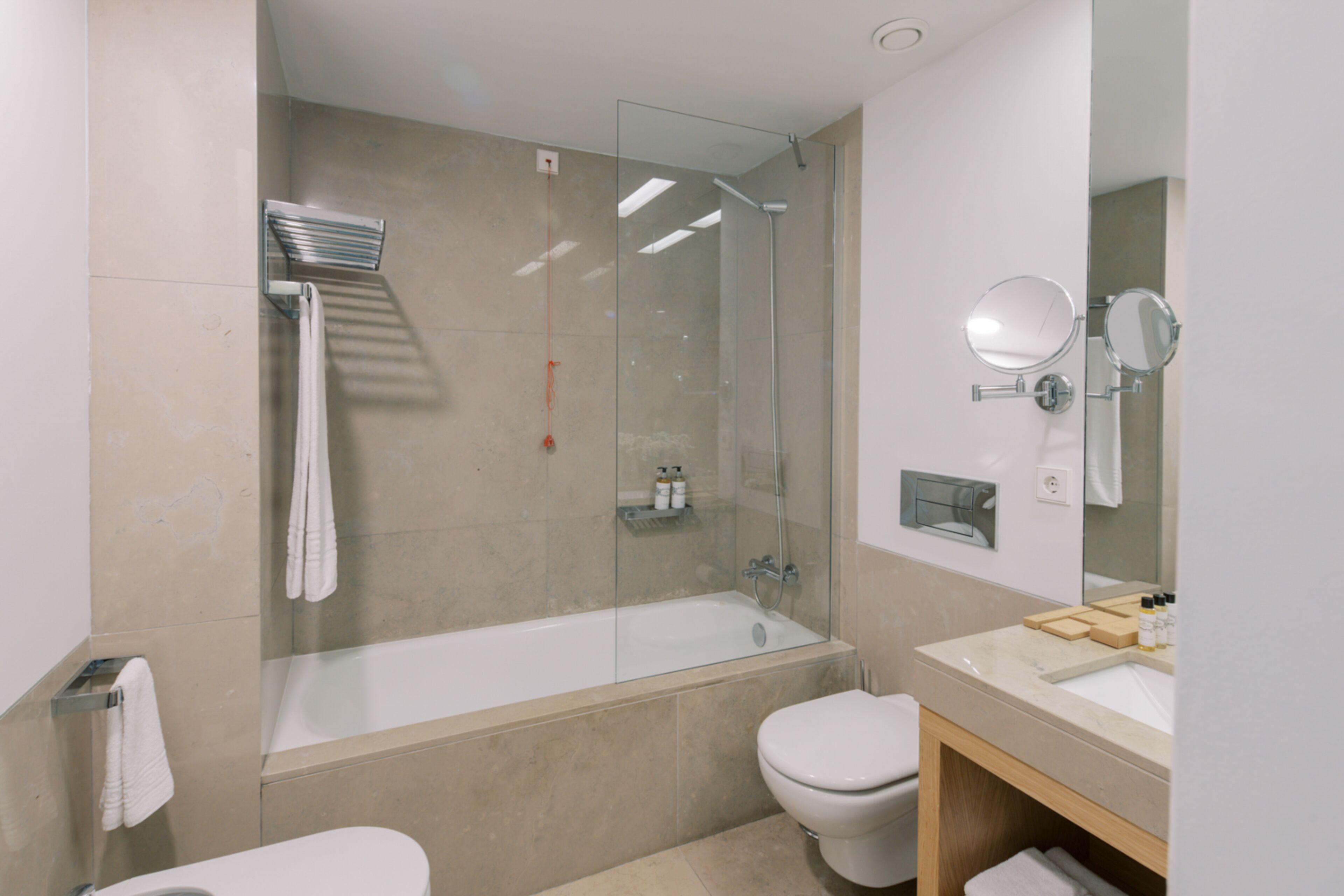 A modern bathroom with a glass-enclosed shower, a bathtub, a toilet, and a vanity with a mirror.