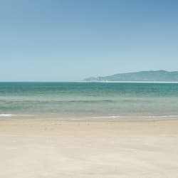 En la playa, arena blanca, sombrillas, vóleibol de playa