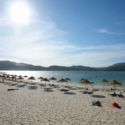En la playa, arena blanca, sombrillas, vóleibol de playa