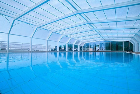 Una piscina al aire libre, sombrillas, sillones reclinables de piscina