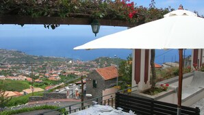 Mesa lista para comer con vista al océano y un pueblo al fondo.