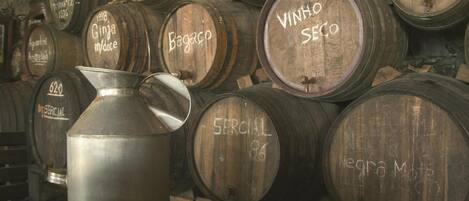 A collection of wooden barrels stacked against a wall, each labeled with different names and years.