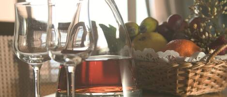 Une table avec une carafe en verre, deux verres à vin et un panier de fruits.