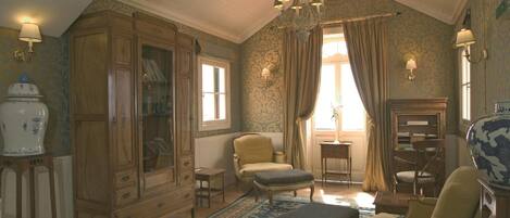 A traditional room with a large wooden cabinet, a chandelier, and a patterned rug.