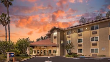 A hotel with a red-tiled entrance, a parking lot, and a sign for the Comfort Inn.
