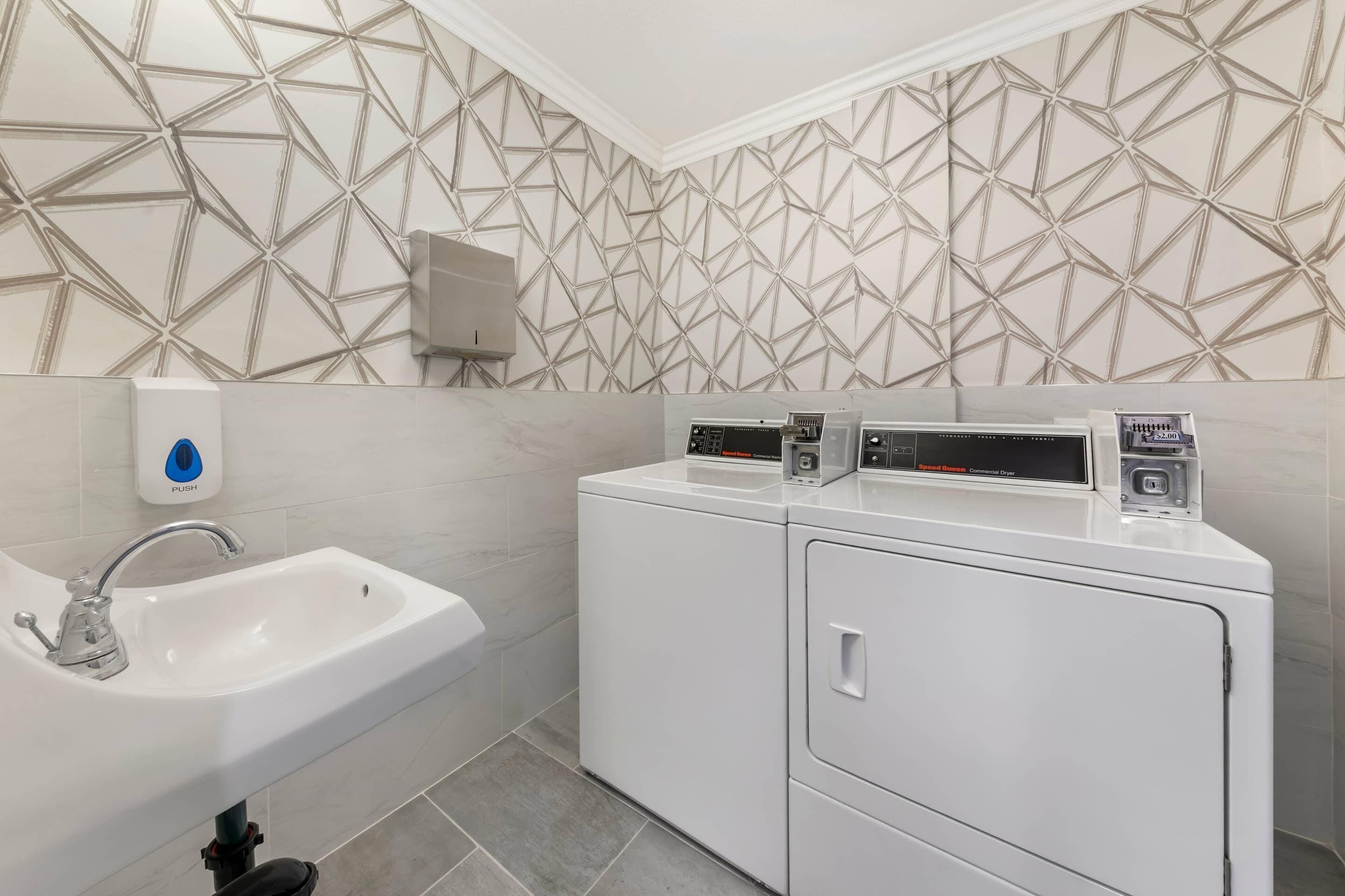 A bathroom with a sink, a hand dryer, and a commercial dryer.