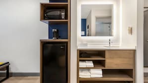 A compact hotel room with a built-in refrigerator, a microwave, a coffee maker, a sink with a mirror, and neatly folded towels. - Comfort Inn Fontana (Fontana)