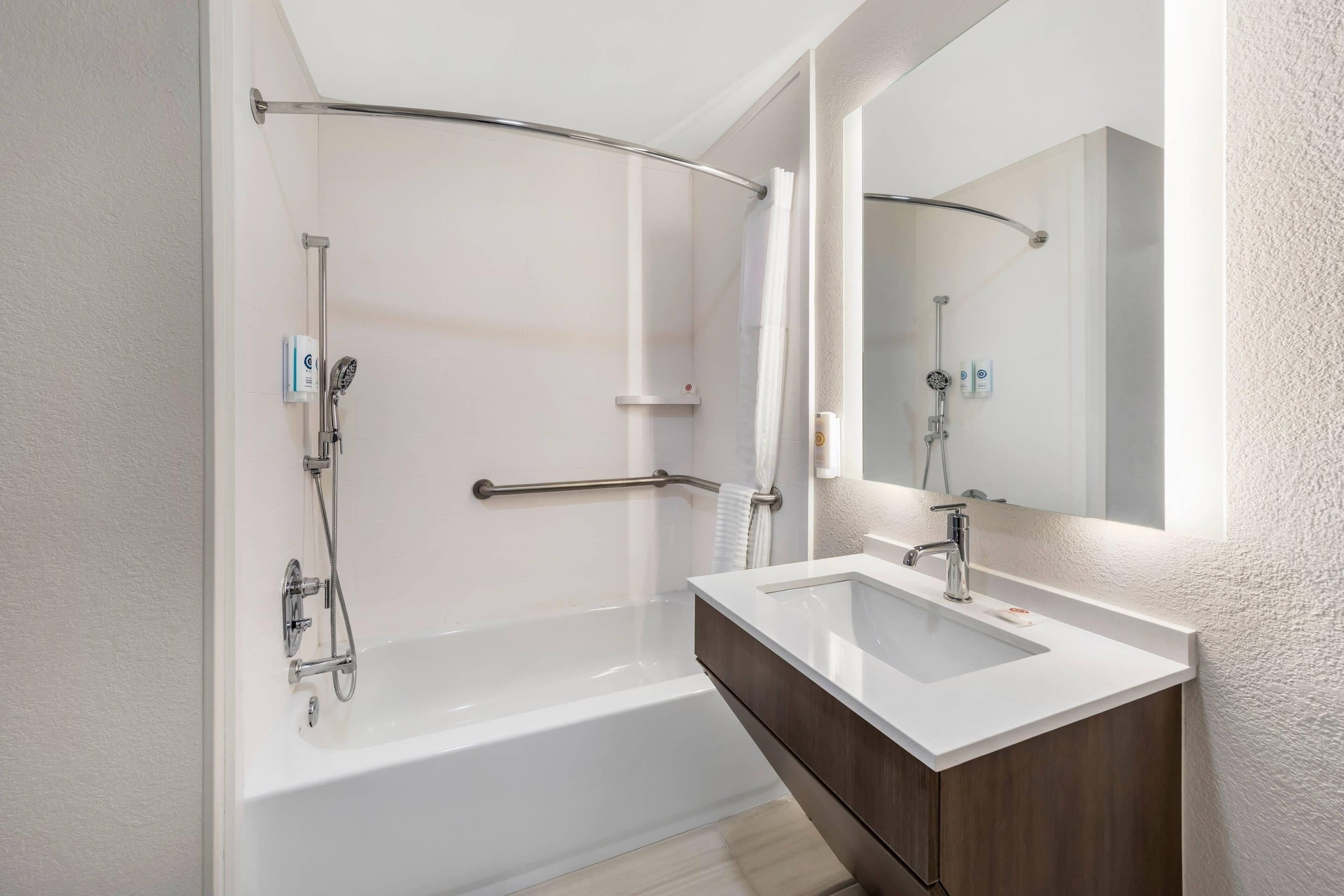 A modern bathroom with a bathtub, a shower, a vanity with a mirror, and a towel rack.