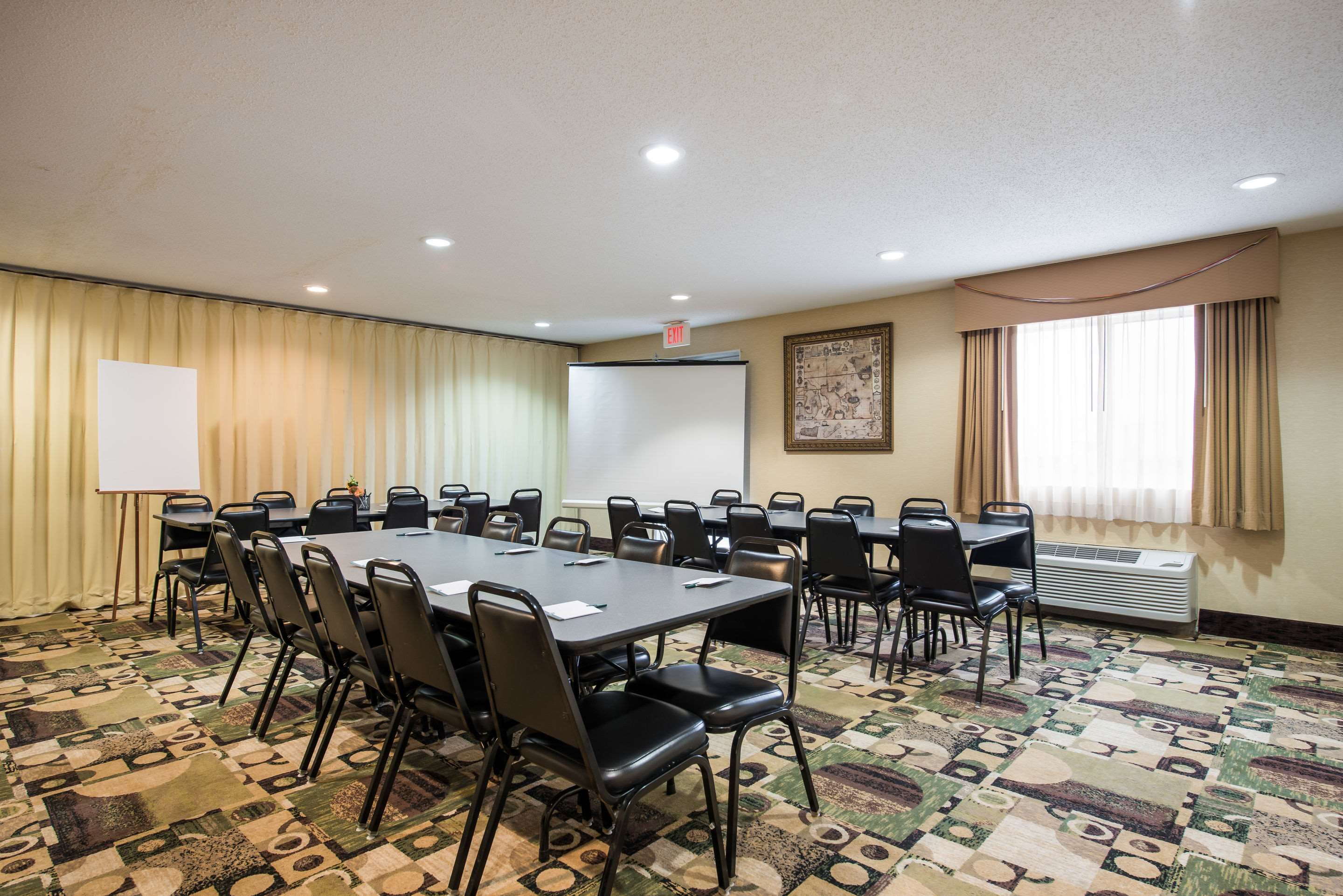 A conference room with a large table, chairs, a whiteboard, and a projector screen.