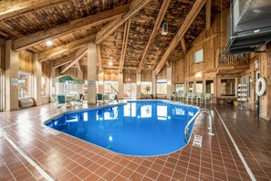 An indoor swimming pool with a wooden ceiling and tiled floor.