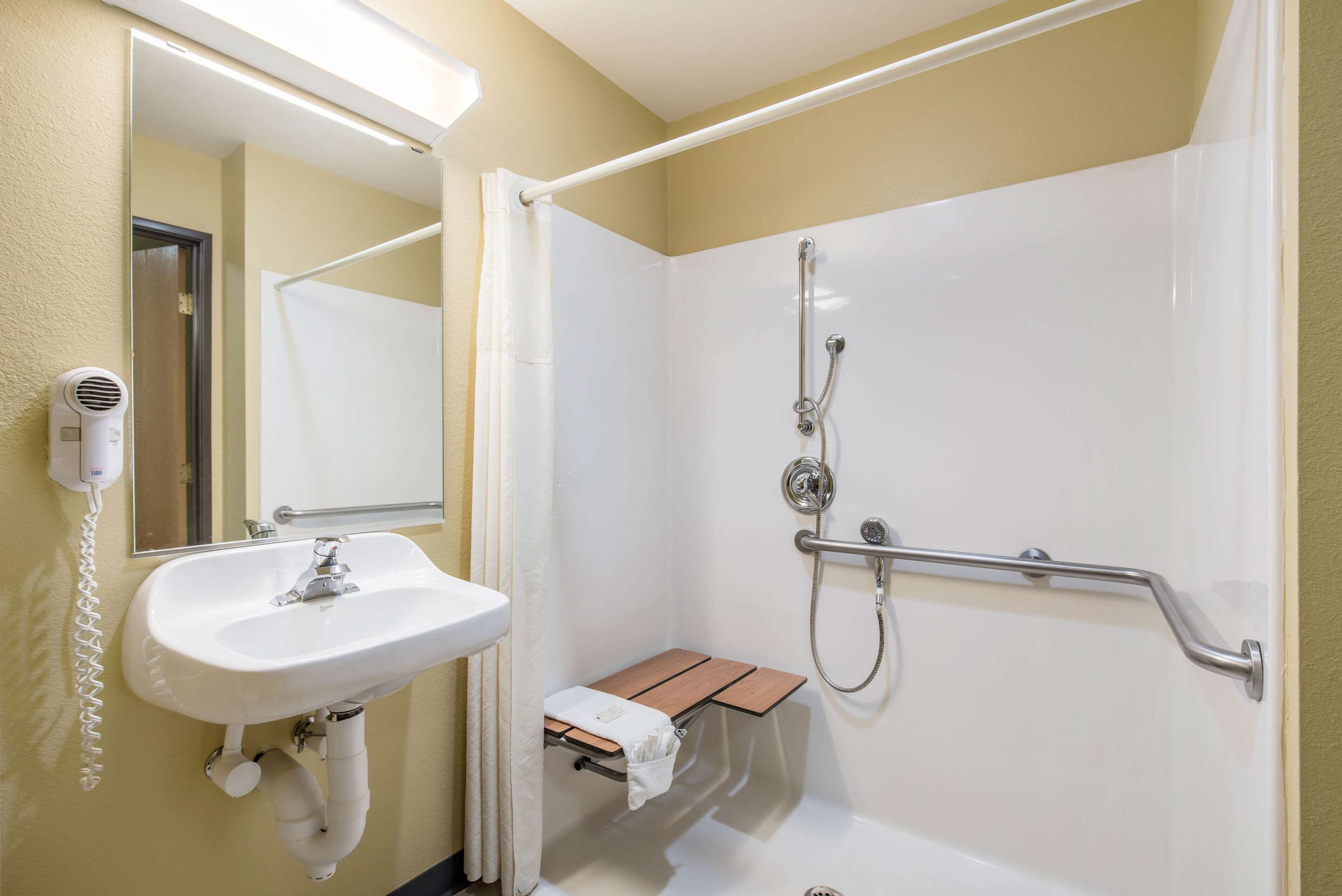 A bathroom with a white sink, a handheld showerhead, and a towel rack.