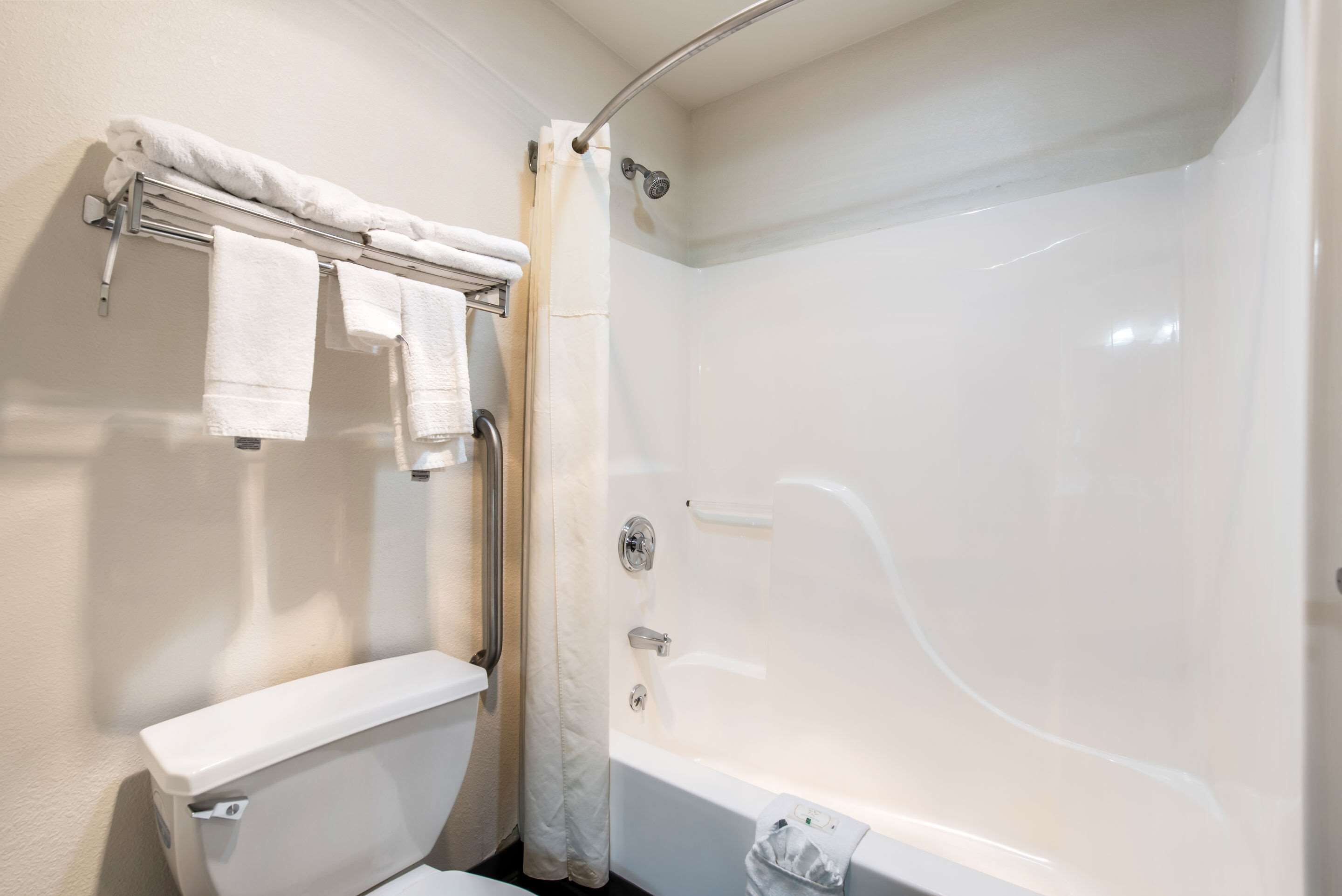 A bathroom with a bathtub, toilet, and towel rack.
