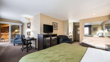 A hotel room with a bed, desk, chair, television, and a bathroom with a bathtub.